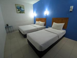 two beds in a room with a blue wall at Midah Inn Puchong in Puchong