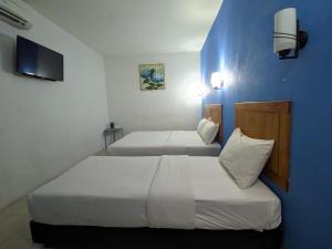 two beds in a room with a blue wall at Midah Inn Puchong in Puchong