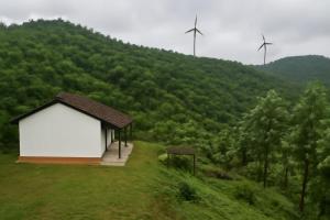 a small building in a field with two wind turbines at wild grove resorts in Varagampadi