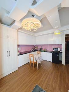 a kitchen with white cabinets and a table with chairs at Căn Hộ Vỹ Dạ Đà Lạt in Da Lat