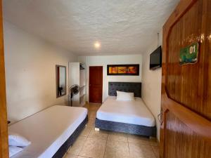 a hotel room with two beds and a tv at Hotel La Casona Quindío Eje Cafetero in Montenegro