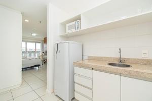 a white kitchen with a sink and a refrigerator at Vision Hotel em Brasília 60300 in Brasília