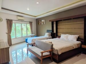 a bedroom with two beds and a chair and a window at K Residence Surabaya in Surabaya +40 photos