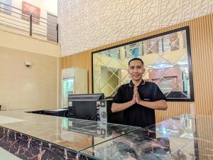 a man standing in front of a counter with his hands claspedly at K Residence Surabaya in Surabaya