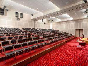 an empty auditorium with chairs and red carpet at Novotel Bucharest City Centre in Bucharest +172 photos