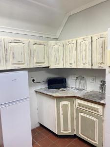 a kitchen with white cabinets and a white refrigerator at Foundry farmhouse in Bothaʼs Hill