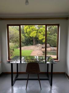 a glass table and a chair in front of a window at Foundry farmhouse in Bothaʼs Hill +7 photos