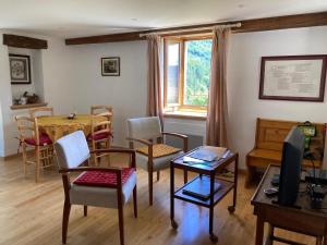 a living room with chairs and a table and a television at Le verger in Vébron
