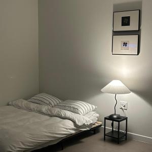 a bedroom with a bed with a lamp on a table at momohouse 체스룸 in Chinyŏng-yŏk