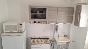 a small kitchen with a microwave and a refrigerator at Condomínio Bélgica in Presidente Prudente +5 photos