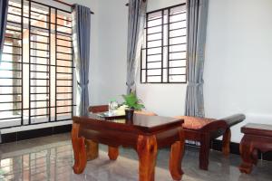 a room with a table and a chair and windows at AHHA Bungalow Kampot in Kampot