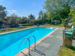 a swimming pool with blue water in a yard at Heron Barn in Hollingbourne +17 photos