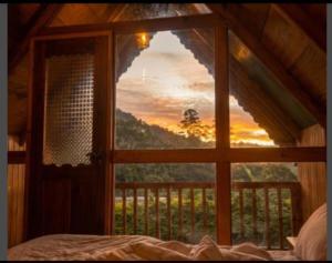 a bedroom with a window looking out at a sunset at Ohiya Our Time Kabana in Ohiya