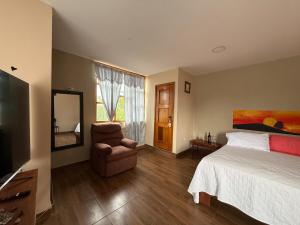 a bedroom with a bed and a chair and a television at DEPARTAMENTO ENCANTO AMAZÓNICO Macas in Macas