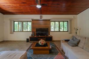 a living room with a couch and a tv at Chacara Morada do Sol com Piscina e Churrasqueira in Sepetiba