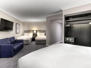 a hotel room with two beds and a blue couch at Sofitel London Gatwick in Horley +231 photos