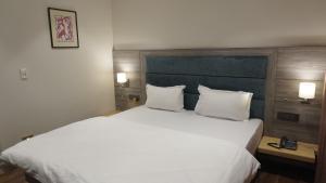 a bedroom with a large white bed with two pillows at The LEGACY HOTEL JAMSHEDPUR in Jamshedpur +7 photos