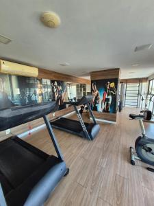 a gym with three tread machines and a wall with pictures at Flat Macambira Home Service in Campina Grande