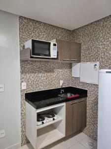 a small kitchen with a microwave and a sink at Flat Macambira Home Service in Campina Grande