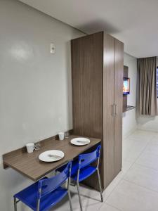 a table with two blue chairs and a wooden cabinet at Flat Macambira Home Service in Campina Grande