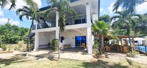 a house with palm trees in front of it at Casa Feliz Ocean Resort in Siquijor