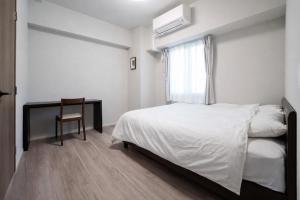 a bedroom with a bed and a desk and a window at Formosa Hills in Kumamoto