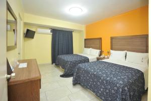 a hotel room with two beds and a television at Hotel del Principado Durango in Durango