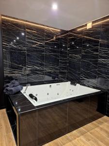 a bath tub in a bathroom with black tiled walls at 007 Loveroom Secrète Jacuzzi privé Cinéma 4K in Courcouronnes