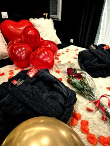 a bed with red balloons and red roses on it at 007 Loveroom Secrète Jacuzzi privé Cinéma 4K in Courcouronnes