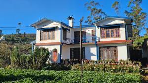 a white house with a fence in front of it at Aurora Residence Nuwara Eliya in Nuwara Eliya