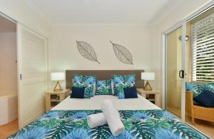 a bedroom with a bed with blue and green pillows at Cayman Villas Port Douglas in Port Douglas +34 photos