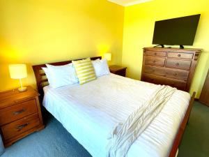 a bedroom with a bed and a dresser with a television at Ocean Whisper in Island Beach