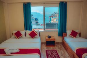 a room with two beds and a large window at Hotel KR Mandap in Pokhara