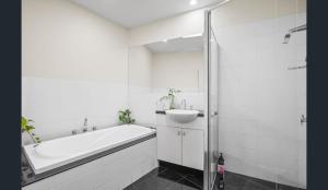 a white bathroom with a tub and a sink at Convenience & Luxury Apartment in Melbourne +21 photos