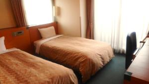 a hotel room with two beds and a window at Kuretake Inn Asahikawa in Asahikawa +22 photos