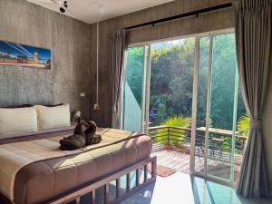 a bedroom with a bed and a large window at BAAN APA ERAWAN Resort in Ban Pong Pat