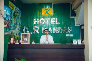 a man standing behind a hotel counter with a sign at Hotel KR Mandap in Pokhara