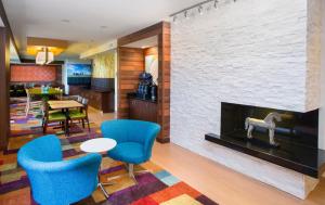 a living room with a fireplace and blue chairs at Fairfield Inn & Suites by Marriott Quincy in Quincy