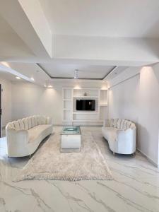 a living room with two white couches and a tv at Villa 37 in Dhamni