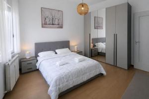 a bedroom with a large bed with white sheets and mirrors at Casa Serena in Baveno +5 photos