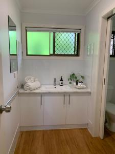 a white bathroom with a sink and a window at Hidden Gem at The Bay - Resort Pool - 300m to Beach in Urangan