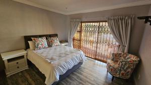 a bedroom with a bed and a chair and a window at Grobler's Haven On Vaal - Barrage in Tumahole +33 photos