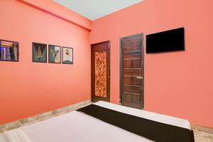 a bedroom with orange walls and a bed and a flat screen tv at Super Hotel O Shalimar Railway Junction Howrah in Garden Reach