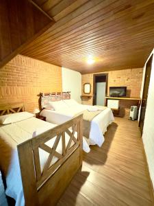 a bedroom with two beds and a wooden wall at Pousada do Sino - 2 min do Capivari in Campos do Jordão