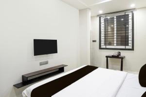 a bedroom with a bed and a television on the wall at Super Townhouse Rajendra Nagar Main Road in Indore
