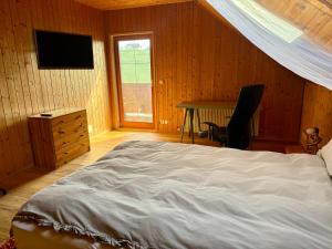 a bedroom with a bed and a desk and a television at Das Holzhaus in Haidershofen
