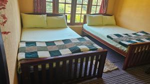 two twin beds in a room with a window at Aurora Residence Nuwara Eliya in Nuwara Eliya