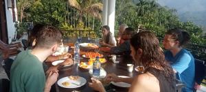 a group of people sitting around a table eating food at Devil mountain villa- kalupahana in Etimole