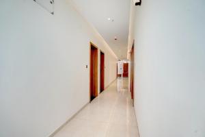 a corridor in a building with white walls and white floors at Super Townhouse Oak T. Narasipura Road Formerly Hotel Nishara in Mysore