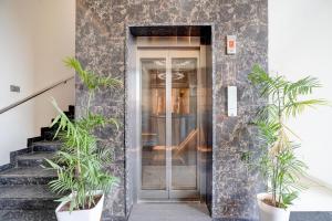 a glass door to a building with potted plants at Super Townhouse Oak T. Narasipura Road Formerly Hotel Nishara in Mysore